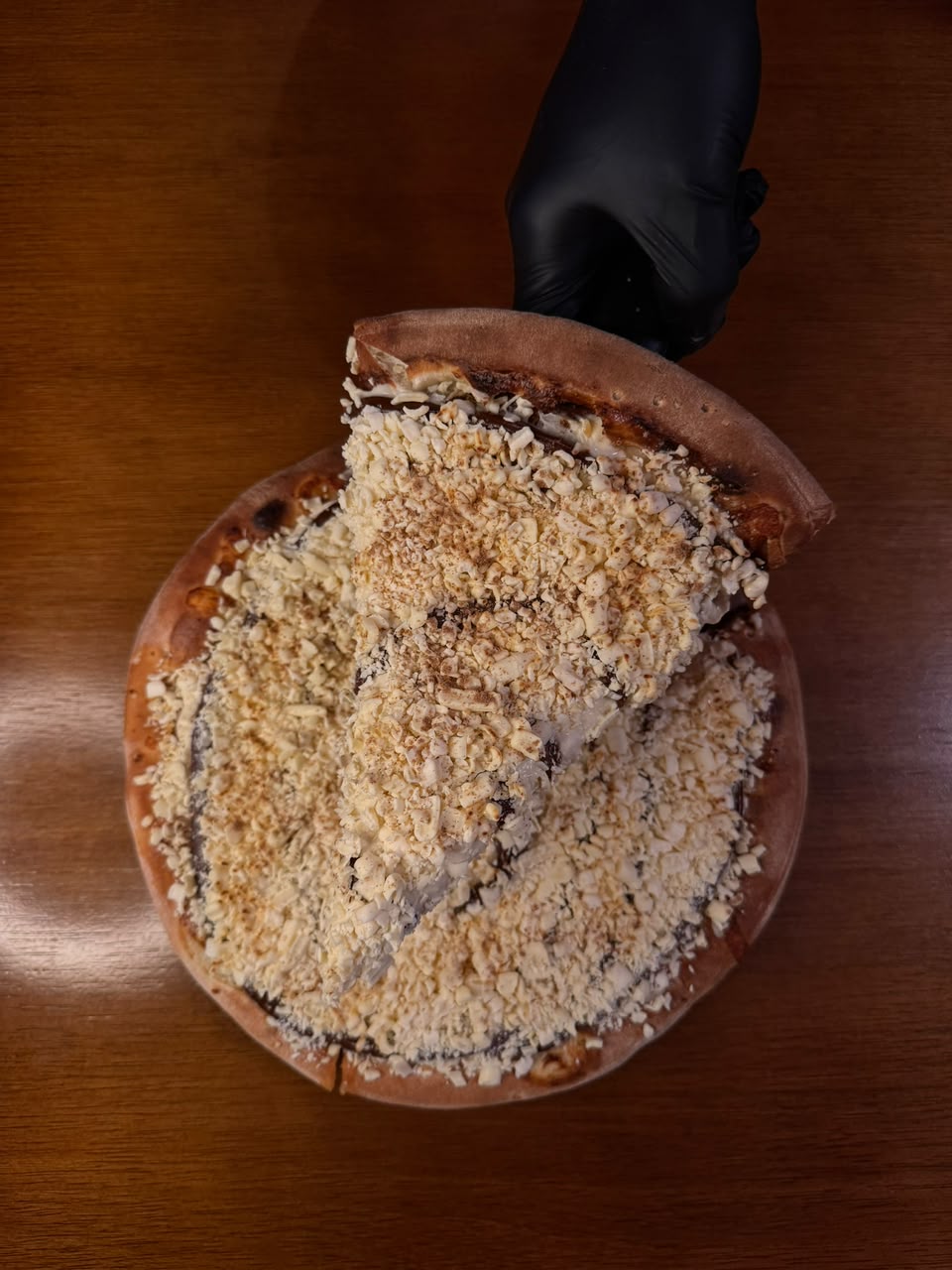 Pizza doce coberta com chocolate branco ralado e fio de chocolate ao leite